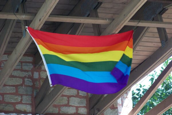 A rainbow flag waving on a porch.