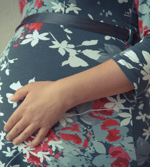 A pregnant woman in a dark blue dress with flowers.
