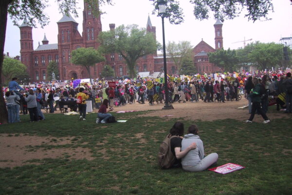A large group of people are gathered together to protest outside a university.