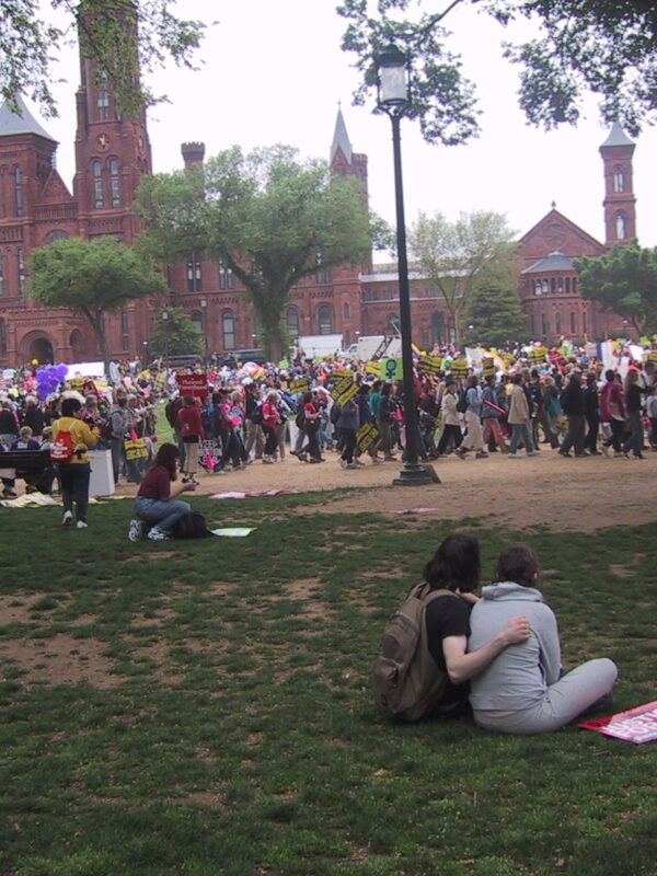 A large group of people are gathered together to protest outside a university.