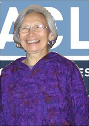 A picture of Joan Hamilton, an elderly Alaska Native woman, standing against an ACLU banner.