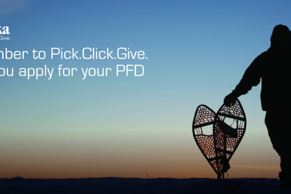 A man is pictured from behind holding a pair of snowshoes against a sunset backdrop.