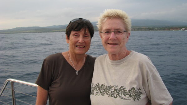 Two women stand on a boat out at sea.