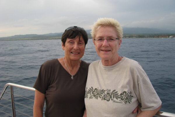 Two women stand on a boat out at sea.