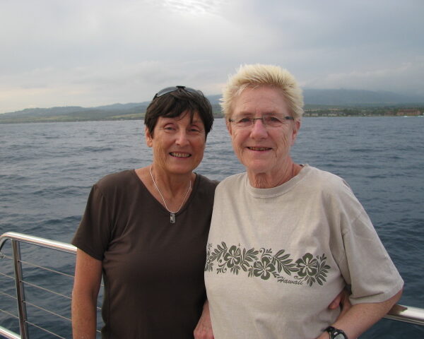Two women stand on a boat out at sea.