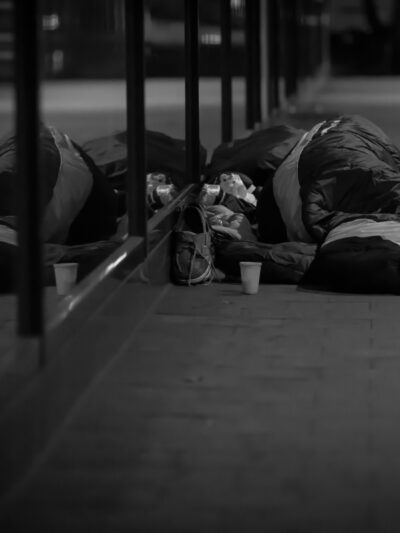 A black and white photo of a man sleeping on the street.