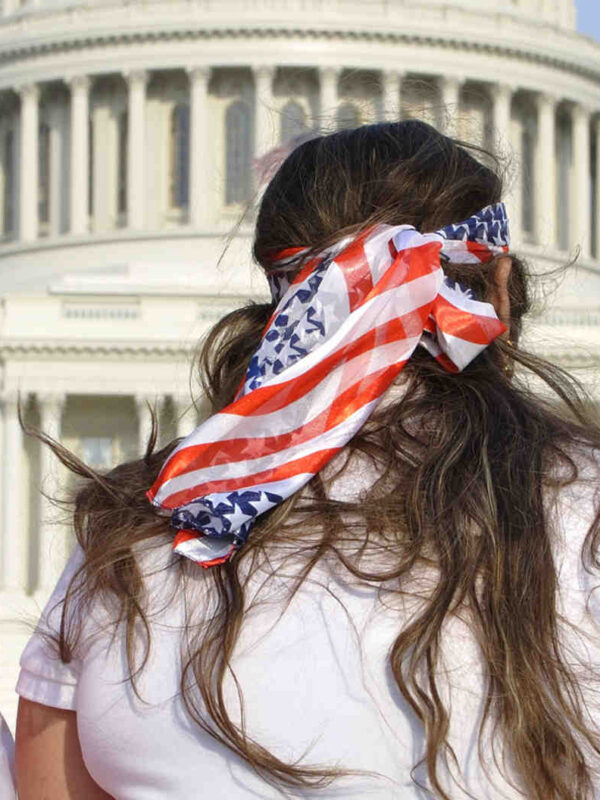Three women in front of the Capitol, two draped in American flags.