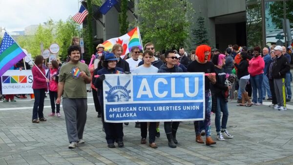 A group of people marching behind the ACLU banner.