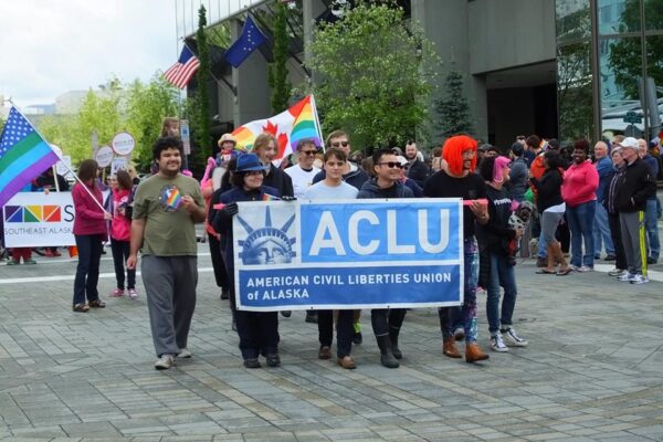 A group of people marching behind the ACLU banner.