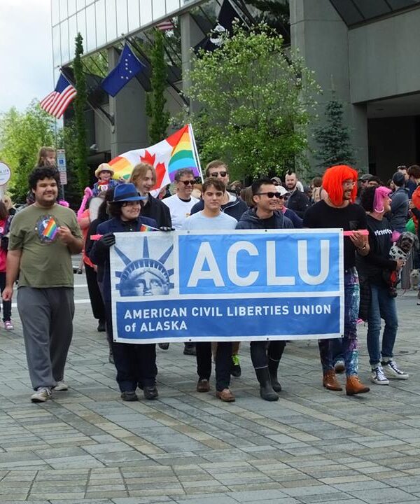 A group of people marching behind the ACLU banner.