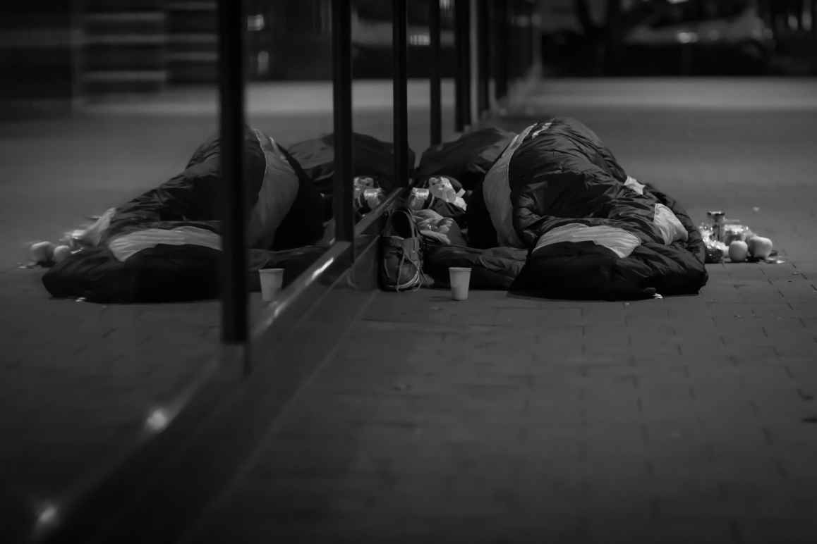 A black and white photo of a man sleeping on the street.