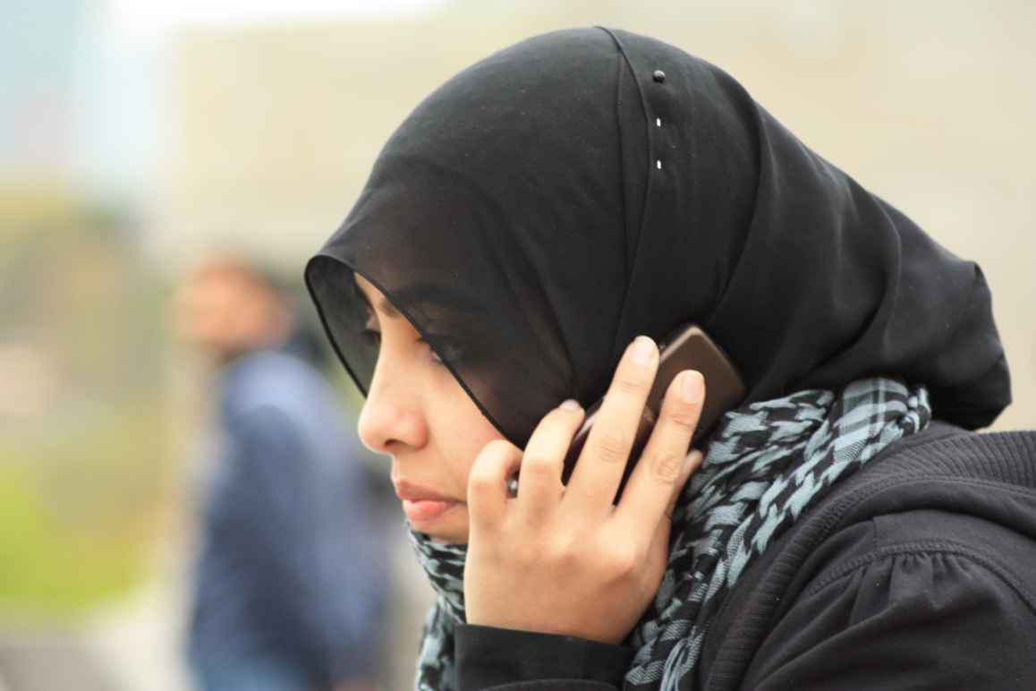 A woman in a black hijab used a smartphone