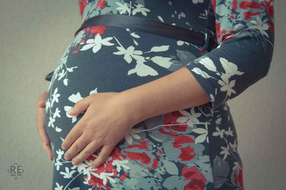 A pregnant woman in a dark blue dress with flowers.