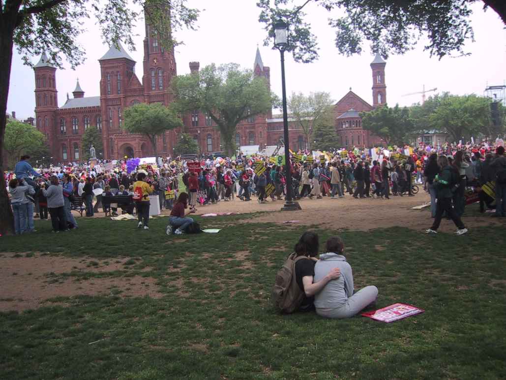 A large group of people are gathered together to protest outside a university.