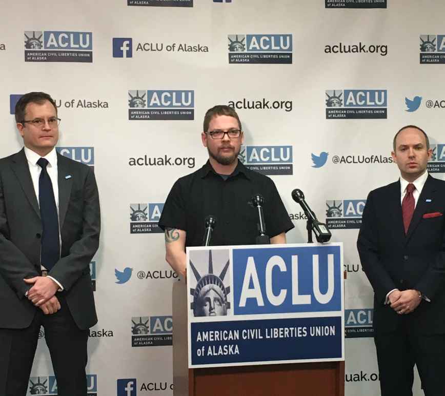 ACLU staff attorney Eric Glatt, plaintiff Lance Hunt, and executive director Joshua Decker stand in front of a podium