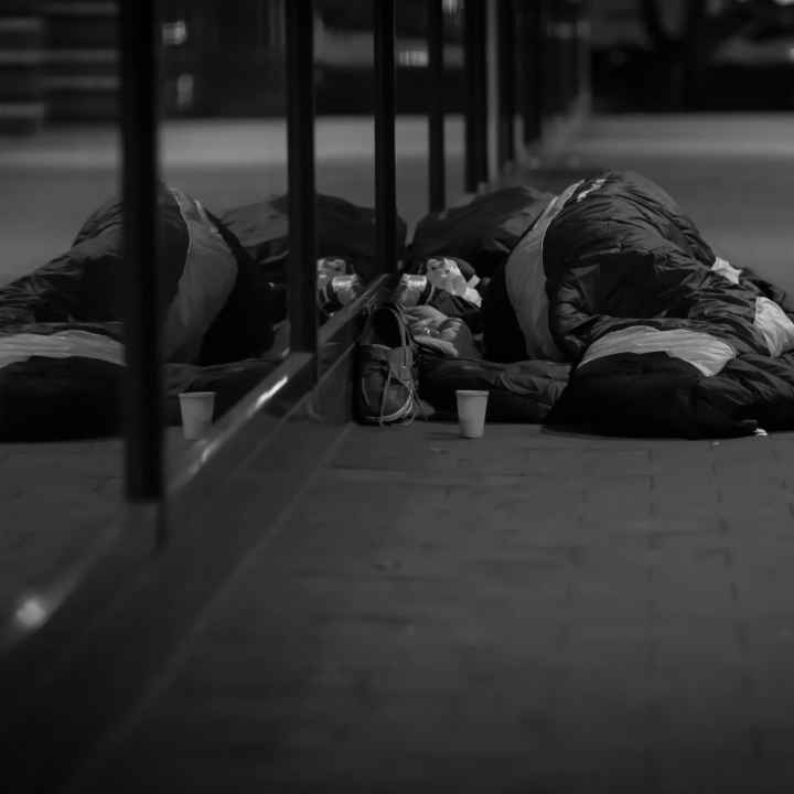 A black and white photo of a man sleeping on the street.