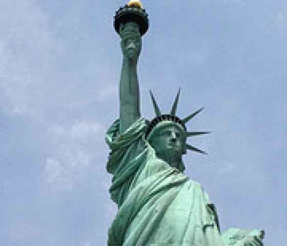 The Statue of Liberty pictured from below against a blue sky.