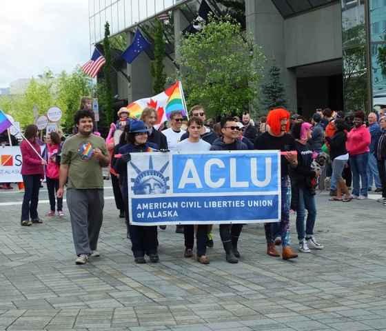 A group of people marching behind the ACLU banner.